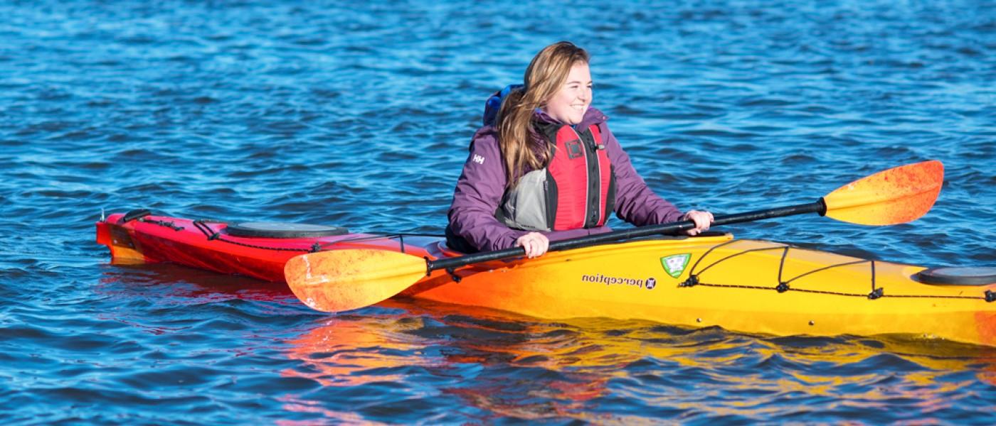 A student kayaks in a river